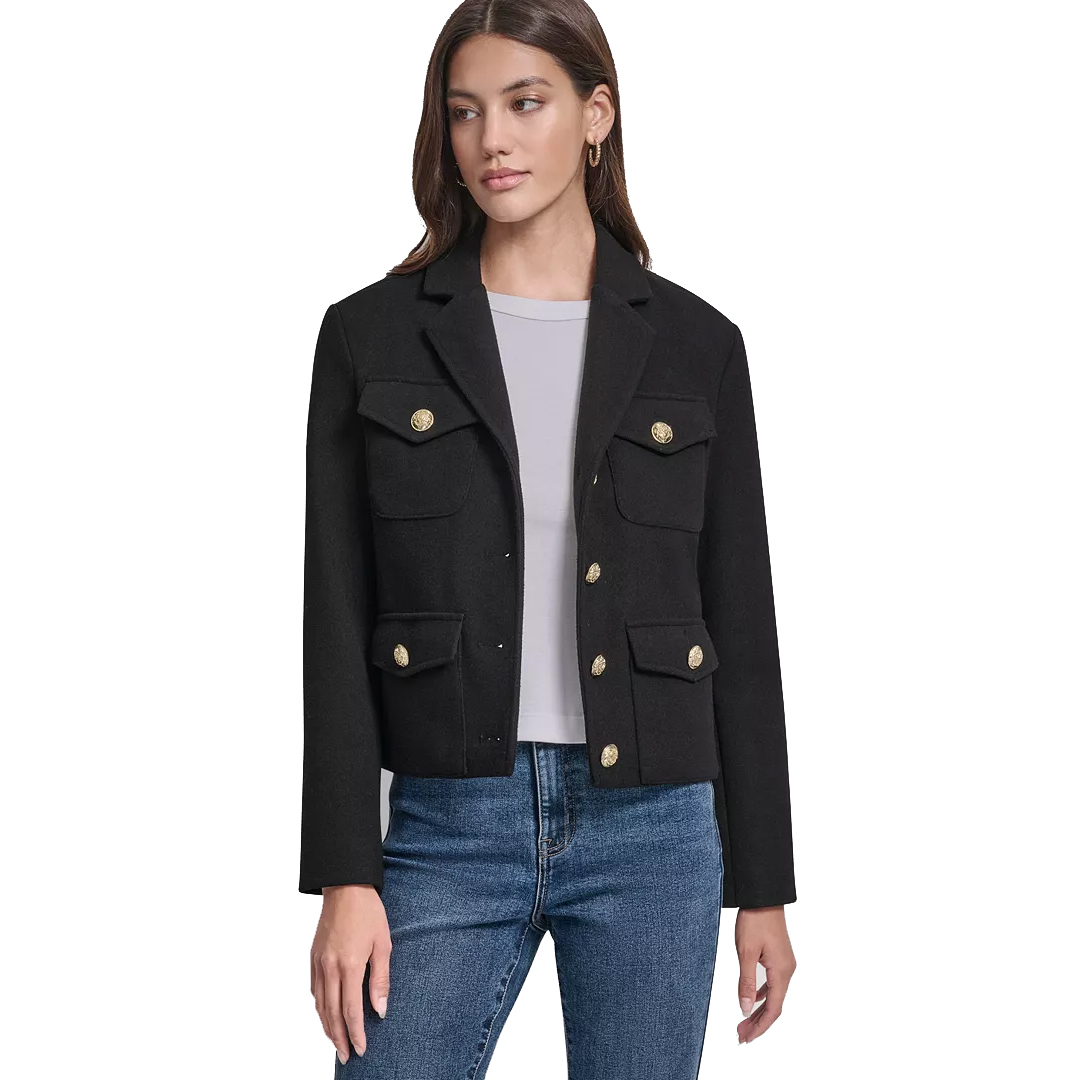 A woman is wearing a black tailored jacket with gold buttons, featuring two chest pockets and two lower pockets. She pairs it with a gray top and blue jeans.