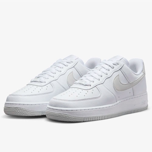 A pair of white low-top sneakers with a distinct swoosh logo on the side.
