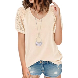 A cream-colored, short-sleeve top with a waffle knit body and lace detailing on the sleeves, paired with denim shorts.