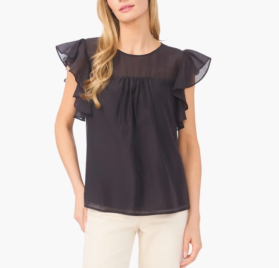 Black short-sleeve blouse with ruffle detailing on the sleeves, paired with light-colored pants.