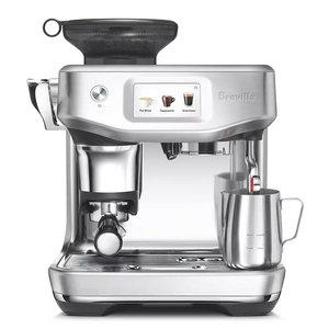 A silver Breville espresso machine with a digital display, featuring options for Flat White, Cappuccino, and Americano. It includes a milk frother and a stainless steel jug.