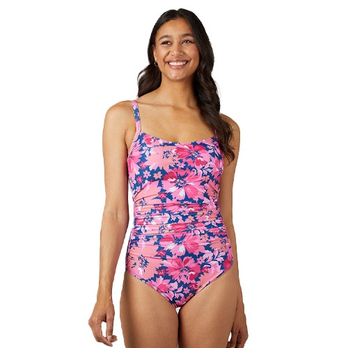 A woman is wearing a pink floral one-piece swimsuit with adjustable straps and ruched detailing around the waist.