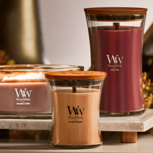 Three WoodWick candles with wooden lids: Patchouli Crème, Golden Bourbon, and Rouge Oud.