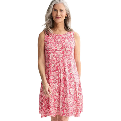 A woman is wearing a sleeveless, knee-length dress with a red floral pattern on a white background.