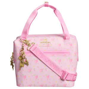 A pink floral Stanley and LoveShackFancy collaboration cooler bag with gold accents and charms, featuring a shoulder strap and top handles.