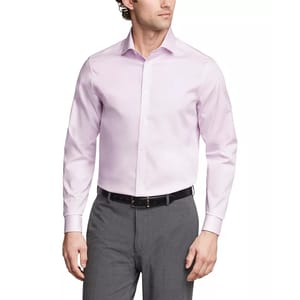 A man is wearing a light pink Calvin Klein dress shirt with long sleeves and a classic collar, paired with gray trousers and a black belt.