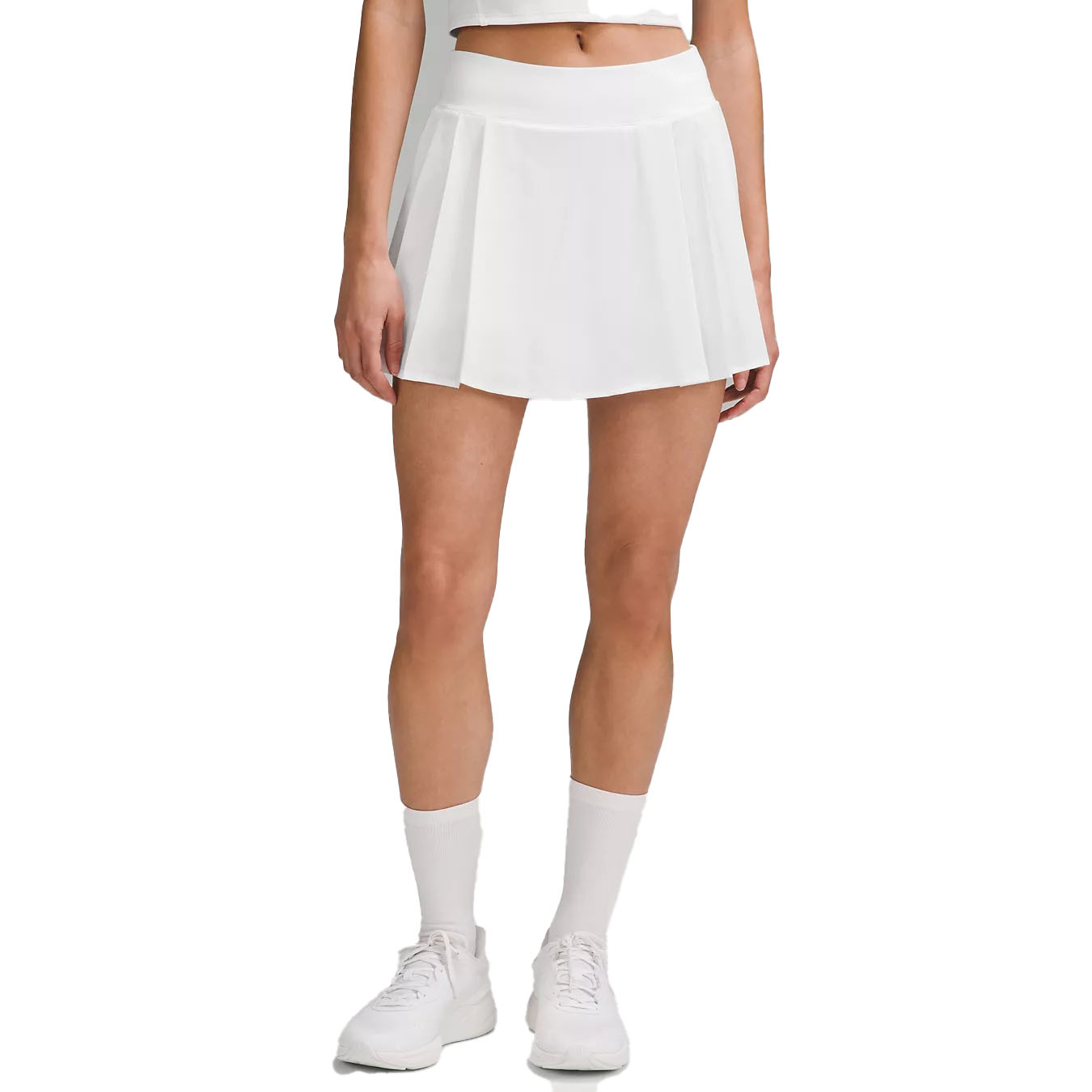 White lululemon tennis skirt with a pleated design, featuring a high waistband. Paired with white socks and sneakers.