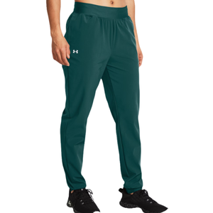 Teal UA Rival High-Rise Woven Pants for women feature an elastic waistband, side pockets, a relaxed fit, and the Under Armour logo on the left thigh. Paired with black athletic shoes.