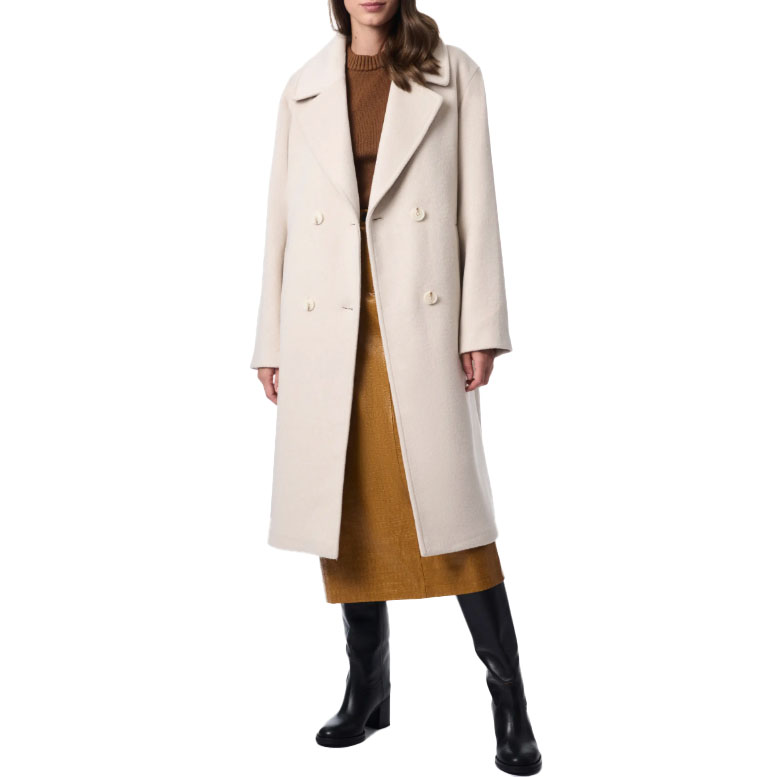 A woman wearing a beige double-breasted coat over a brown sweater and mustard-colored skirt, paired with black knee-high boots.