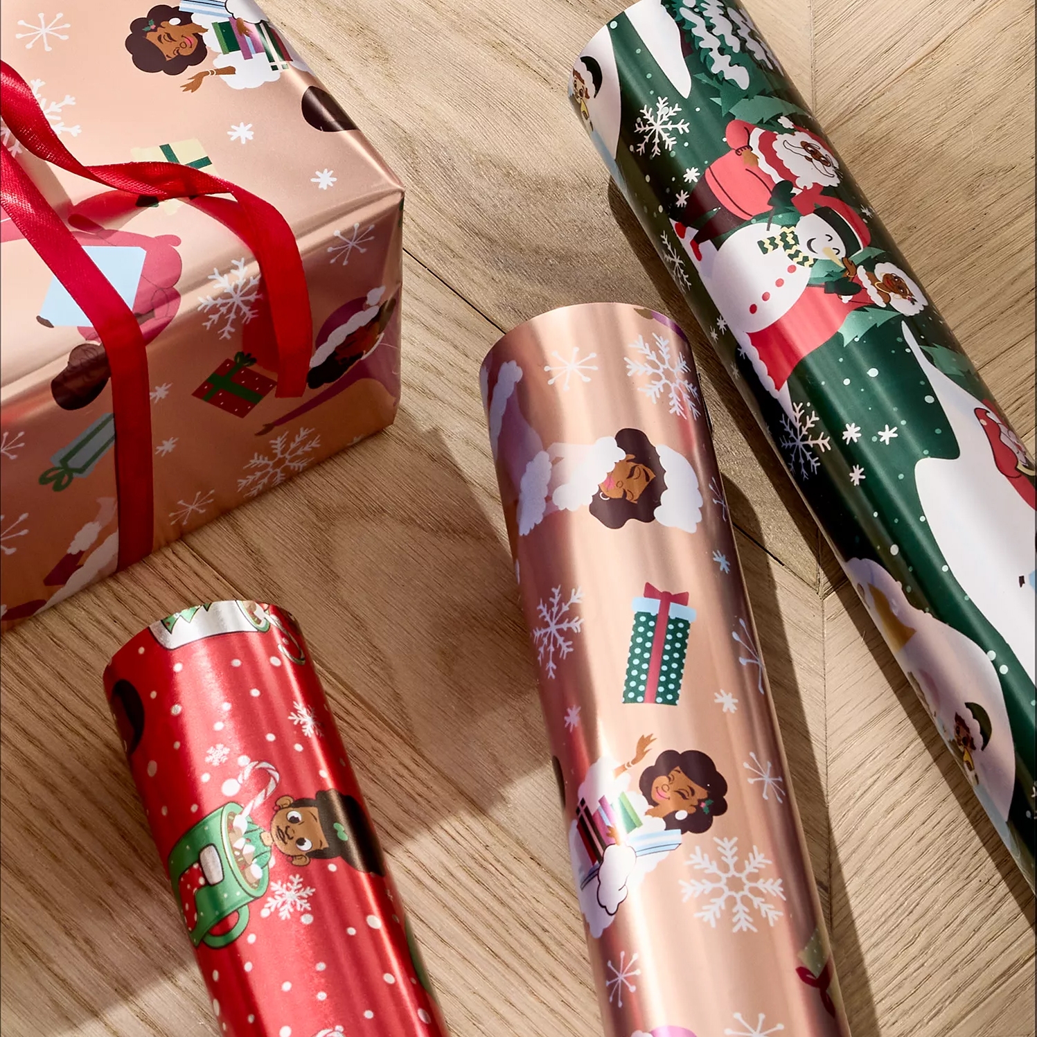 The photo shows various rolls of festive wrapping paper featuring diverse characters and Christmas-themed designs, alongside a wrapped gift box with a red ribbon.