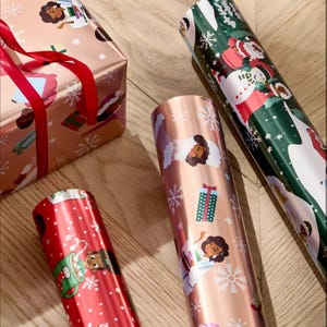 The photo shows various rolls of festive wrapping paper featuring diverse characters and Christmas-themed designs, alongside a wrapped gift box with a red ribbon.