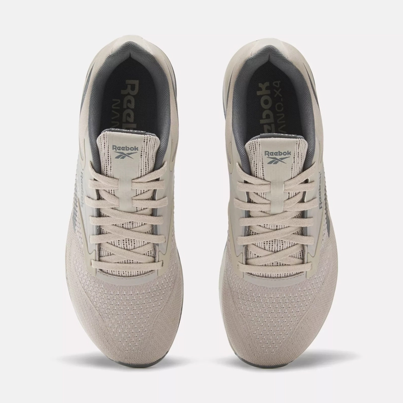 A pair of beige Reebok sneakers facing towards the viewer.