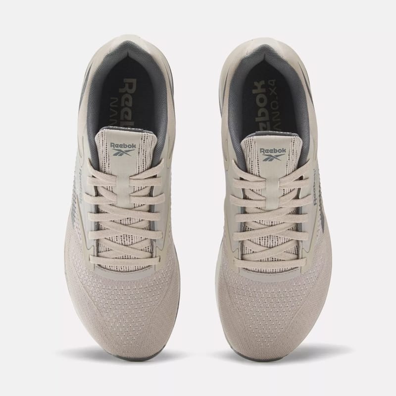 A pair of beige Reebok sneakers facing towards the viewer.