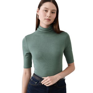 A person wearing a green ribbed turtleneck top with half sleeves, paired with dark blue jeans and a black belt.
