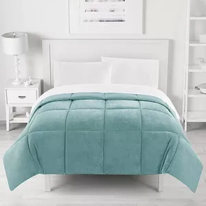 A neatly made bed features a light teal checkered comforter with white sheets, a white headboard, a white nightstand with a lamp on the left, and shelves on the wall to the right.
