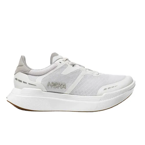 Hoka Transport X Shoes feature a sleek, all-white design with a breathable mesh upper, cushioned sole, and subtle branding on the side. They are designed for comfort and style, suitable for running or casual wear.