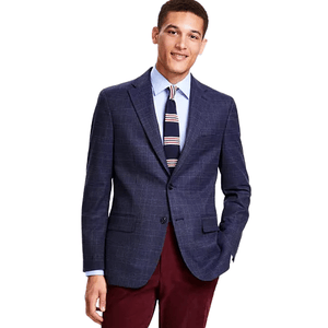A man wears a navy checked Tommy Hilfiger sport coat with a two-button closure, paired with a light blue shirt and a striped tie, complemented by burgundy trousers.
