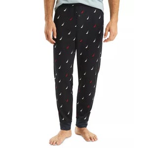 Men's pajama pants with a navy background and a repeating pattern of small sailboat motifs in white and red.