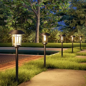 Outdoor path lights on poles illuminate a garden walkway at dusk.