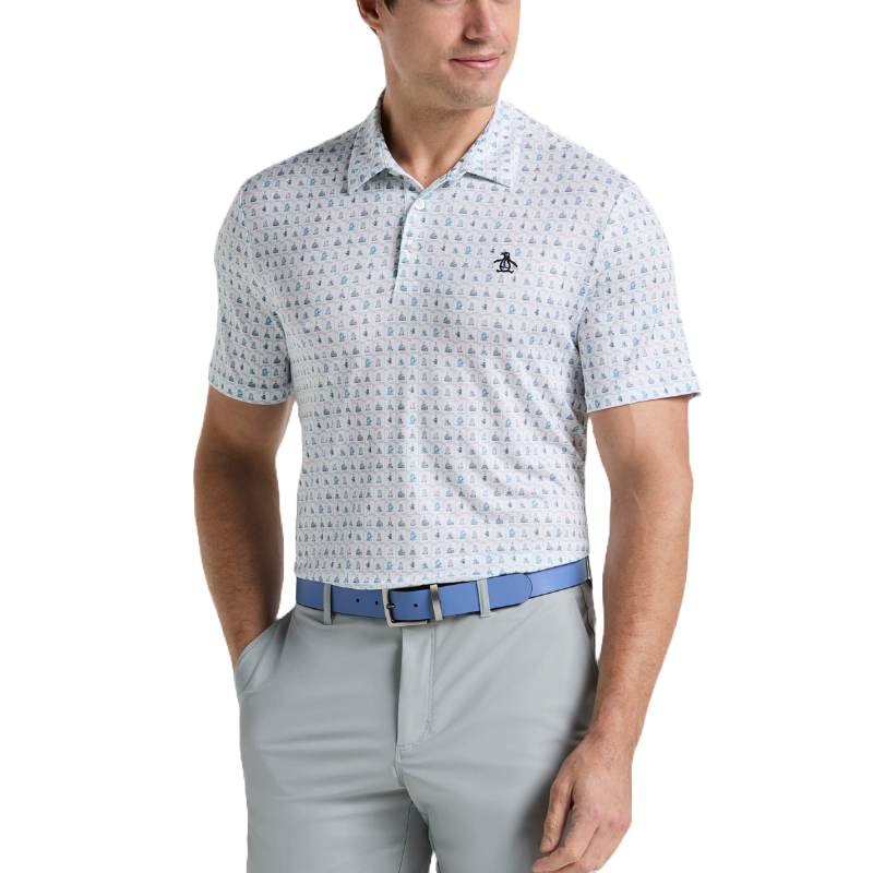 A man is wearing a short-sleeve, light-colored polo shirt with a subtle sailboat pattern and penguin logo, paired with light gray pants and a blue belt.