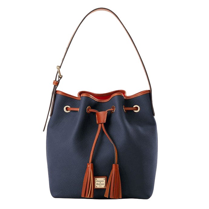 A navy blue drawstring bucket bag with brown leather accents and a single shoulder strap. Features tassels and a metal logo plate.