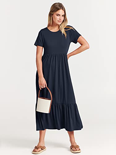 A woman is wearing a navy blue, short-sleeved maxi dress with a ruffled hemline, paired with flat sandals and a two-tone handbag.