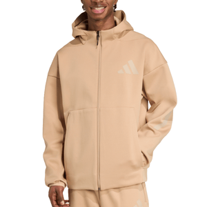 A person wearing a beige Adidas hoodie with a front zipper, large pocket, and logo on the chest and sleeve.