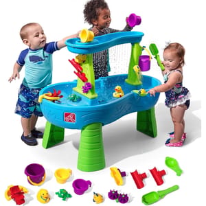 The Step2 Rain Shower Water Table features a blue and green design with multiple play accessories like buckets, scoops, and water wheels, encouraging interactive water play for toddlers.