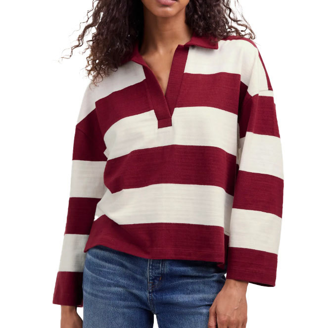 A woman is wearing a long-sleeved rugby-style shirt with maroon and white horizontal stripes, paired with blue jeans.