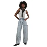 A person is wearing a gray tank top, wide-leg light-wash jeans, a black sweater draped over the shoulders, and black ballet flats.