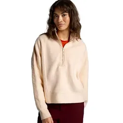 A woman wearing a light peach quarter-zip pullover with a red shirt underneath, paired with maroon pants.