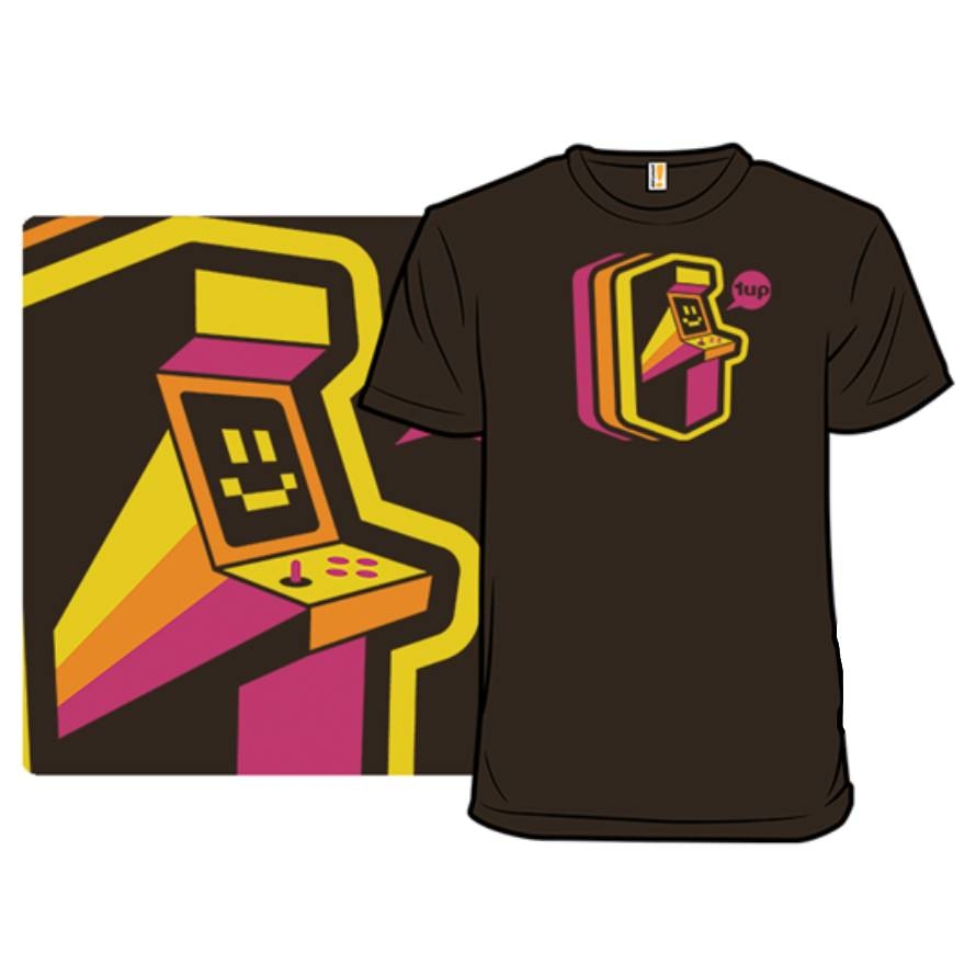 A brown T-shirt features a stylized retro arcade machine design in yellow, orange, and pink, with a smiling face on the screen and the text \“1up.\“