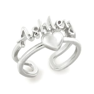 A silver-tone double-row ring featuring the name \“Ashley\“ with a heart shape in the center. The design combines personalized lettering with a stylish split band for a charming look.