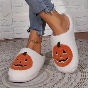 White slippers with orange pumpkin faces embroidered on the top.