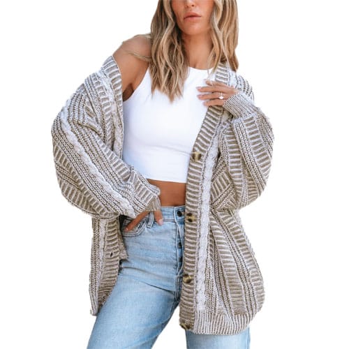A woman is wearing a casual outfit with a beige and white striped chunky knit cardigan over a white sleeveless crop top and light blue jeans.