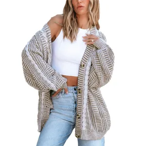 A woman is wearing a casual outfit with a beige and white striped chunky knit cardigan over a white sleeveless crop top and light blue jeans.