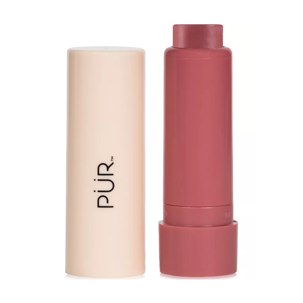 An open stick-shaped cosmetic with a cream-to-powder formula in a light brown container, alongside its cylindrical cap with \“PÜR\“ branding.