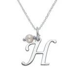 A silver necklace features a pendant in the shape of the letter \“H\“ accompanied by a small pearl charm.