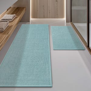 Two light blue bath mats on a bathroom floor, one larger and one smaller, with wooden shelves holding folded towels in the background.