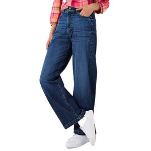 A person is wearing blue jeans with a relaxed fit and white sneakers, paired with a pink checkered shirt.