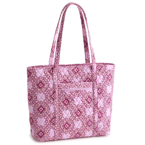 Pink quilted tote bag featuring a symmetrical floral pattern with long handles and an exterior zip pocket.