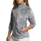 A person is wearing a gray fleece jacket with a logo on the chest, featuring a high collar and front pockets.