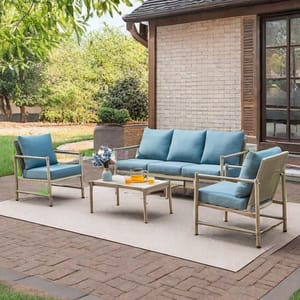 Outdoor patio set with blue cushions, including a sofa, two chairs, and a coffee table on a light-colored rug.