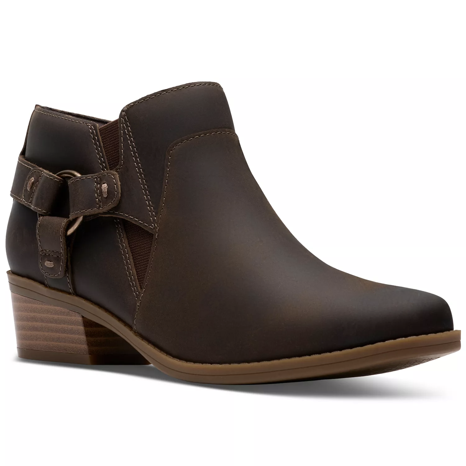 A brown ankle boot with a low stacked heel and decorative buckle strap on the side, featuring a smooth leather finish and subtle stitching accents.