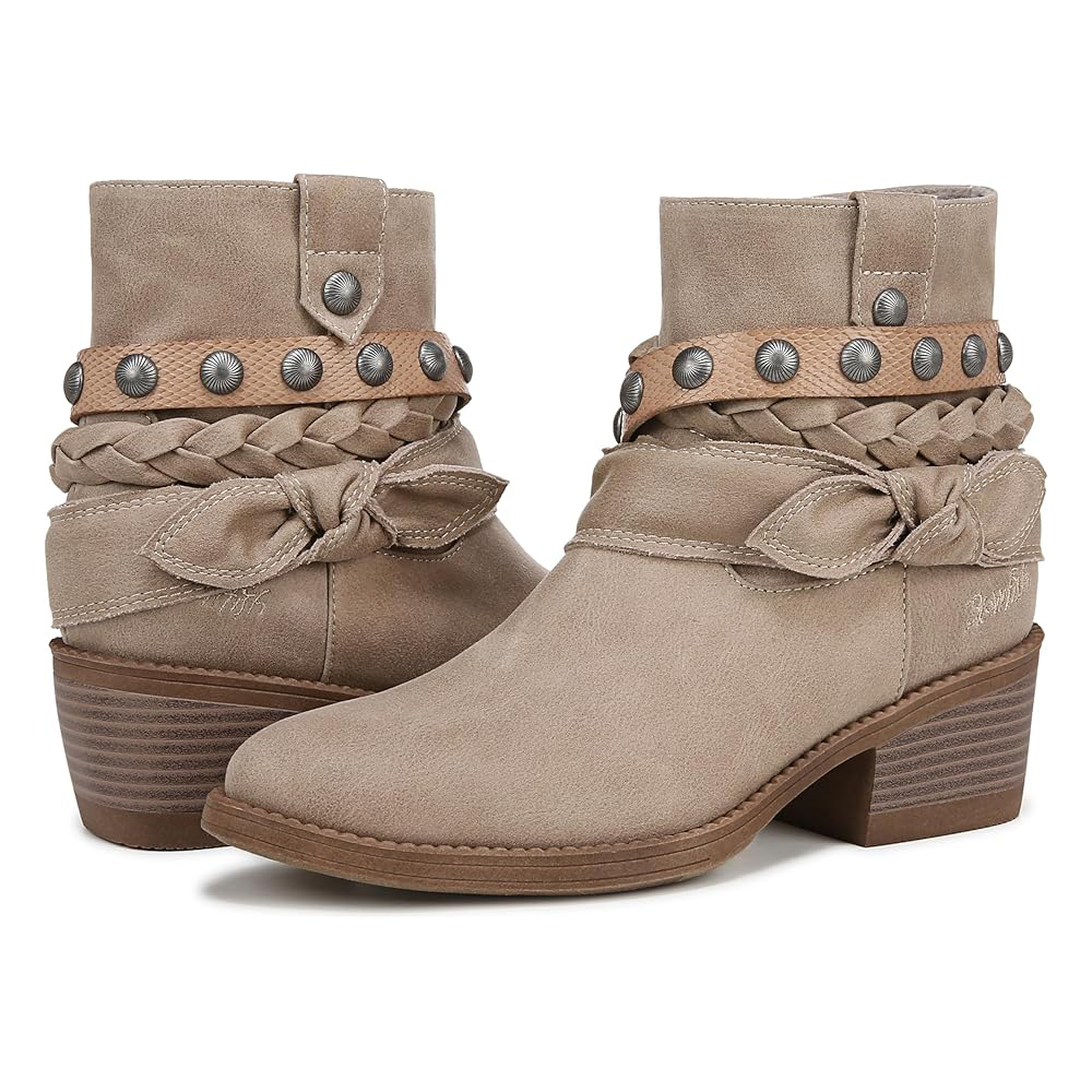 Blowfish Rally Booties are ankle-high boots in a beige suede material, featuring braided and knotted straps around the ankle, metal stud embellishments, and a low stacked heel.