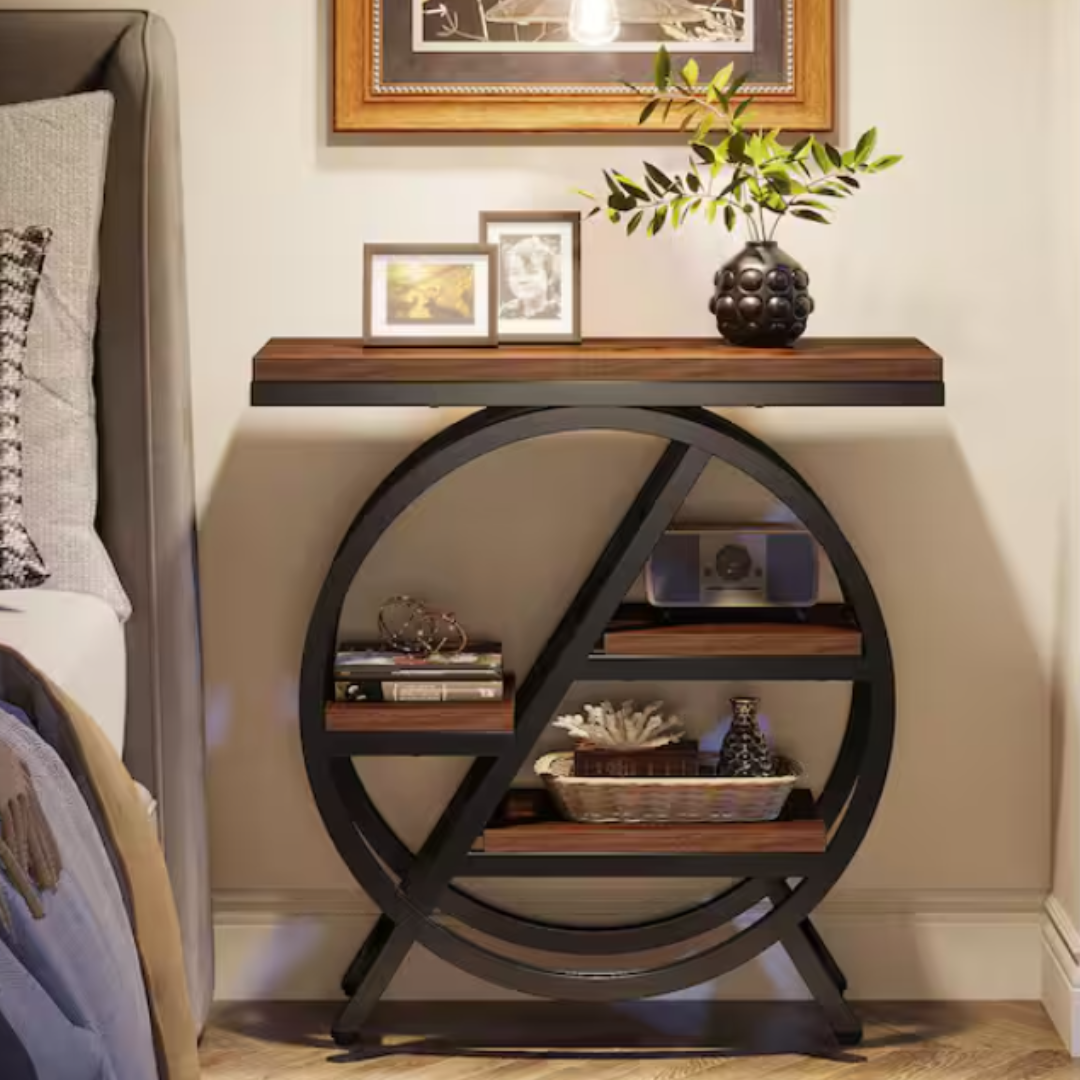 Black metal and wood console table with circular design includes two shelves displaying books, a radio, and decorative items. The tabletop holds framed photos and a vase with green foliage.