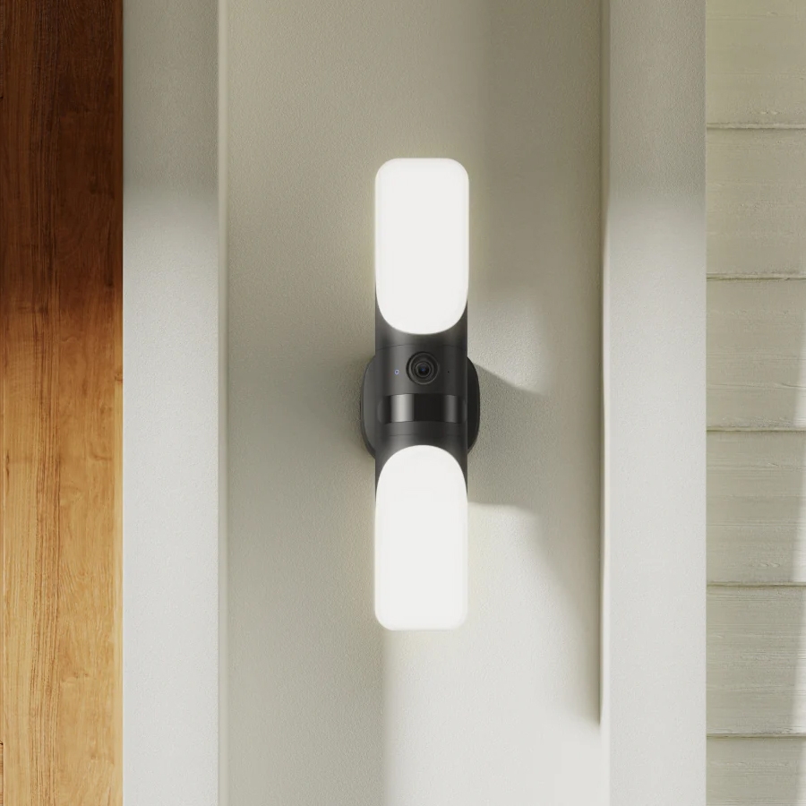 Wall-mounted outdoor security light with built-in camera between two LED panels.