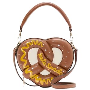 A handbag shaped like a pretzel with decorative icing and the brand name \“Kate Spade\“ on it. It features a detachable strap and handle.