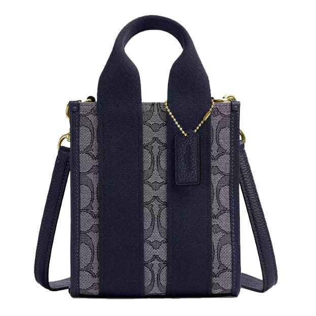 A compact handbag with a navy-blue color scheme, featuring a patterned fabric on the front, wide handles, a detachable shoulder strap, and gold hardware.
