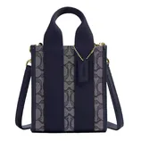 A compact handbag with a navy-blue color scheme, featuring a patterned fabric on the front, wide handles, a detachable shoulder strap, and gold hardware.